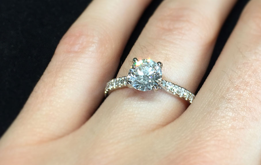classic solitaire engagement ring set in platinum with scallop set diamond shoulders